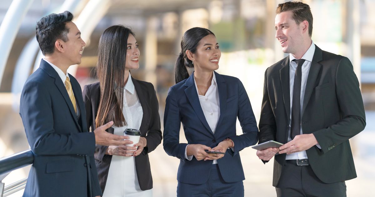 4 corporate professionals wearing formal attire are talking