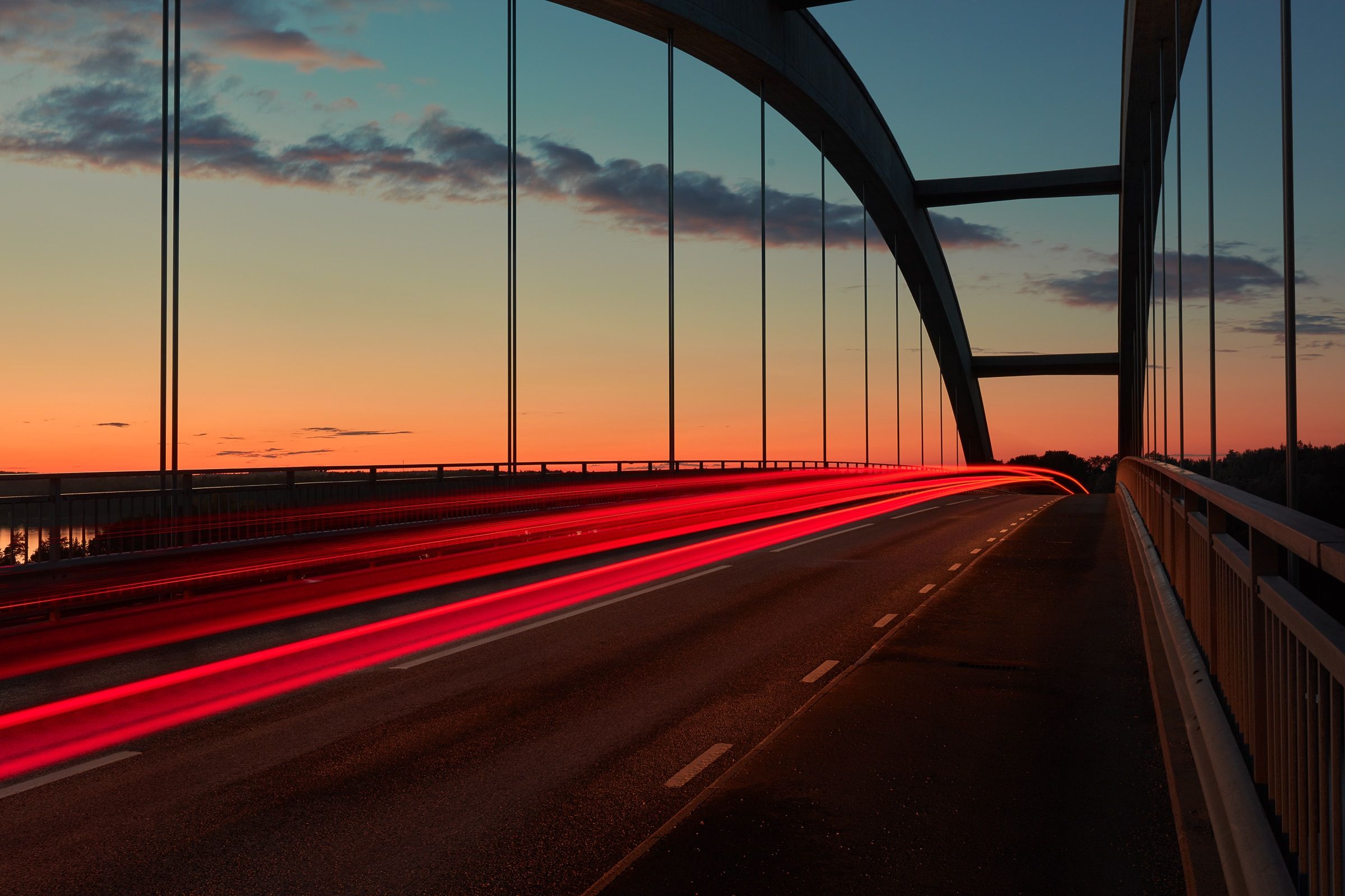 a bridge at sunset with red lights
