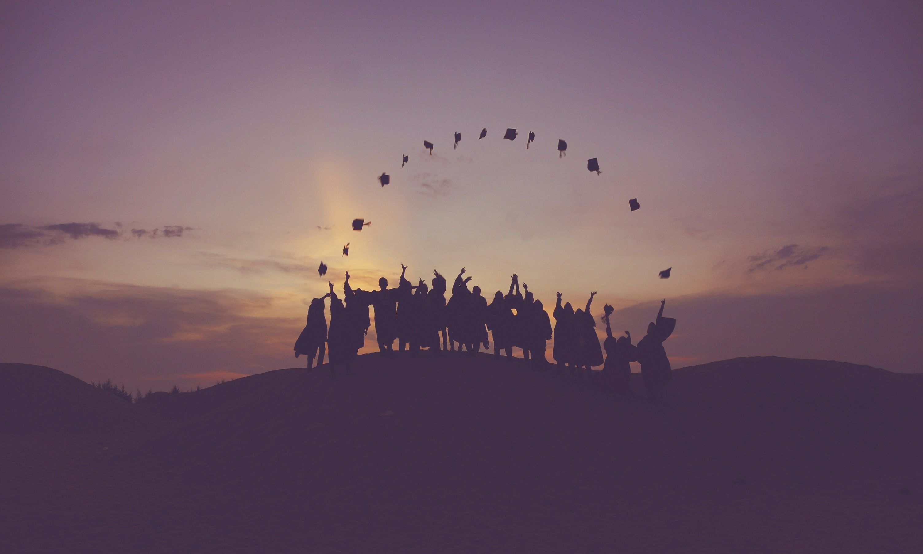 a group of graduates throwing their mortarboard in the air