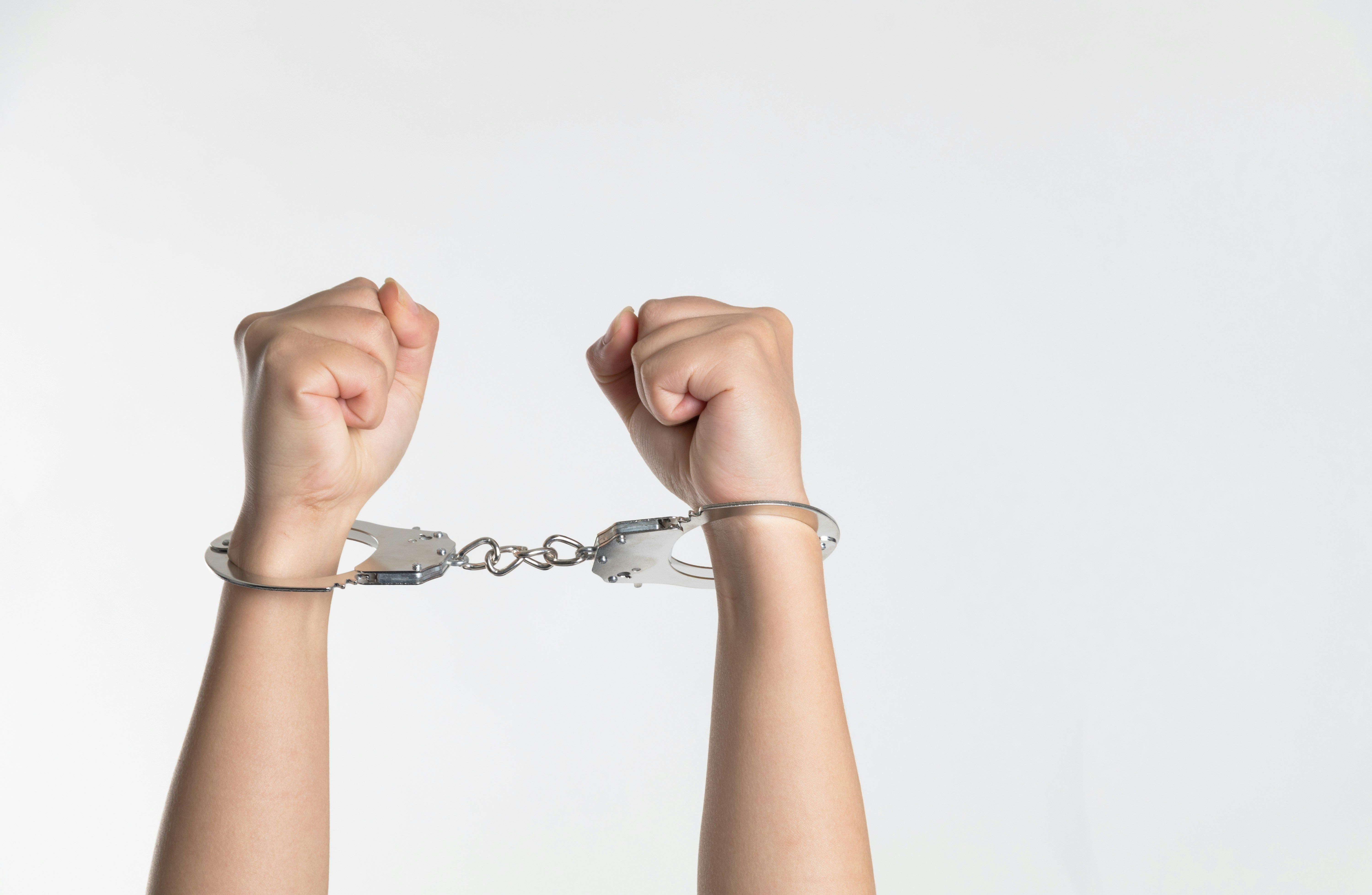 A person in handcuffs showing their arms