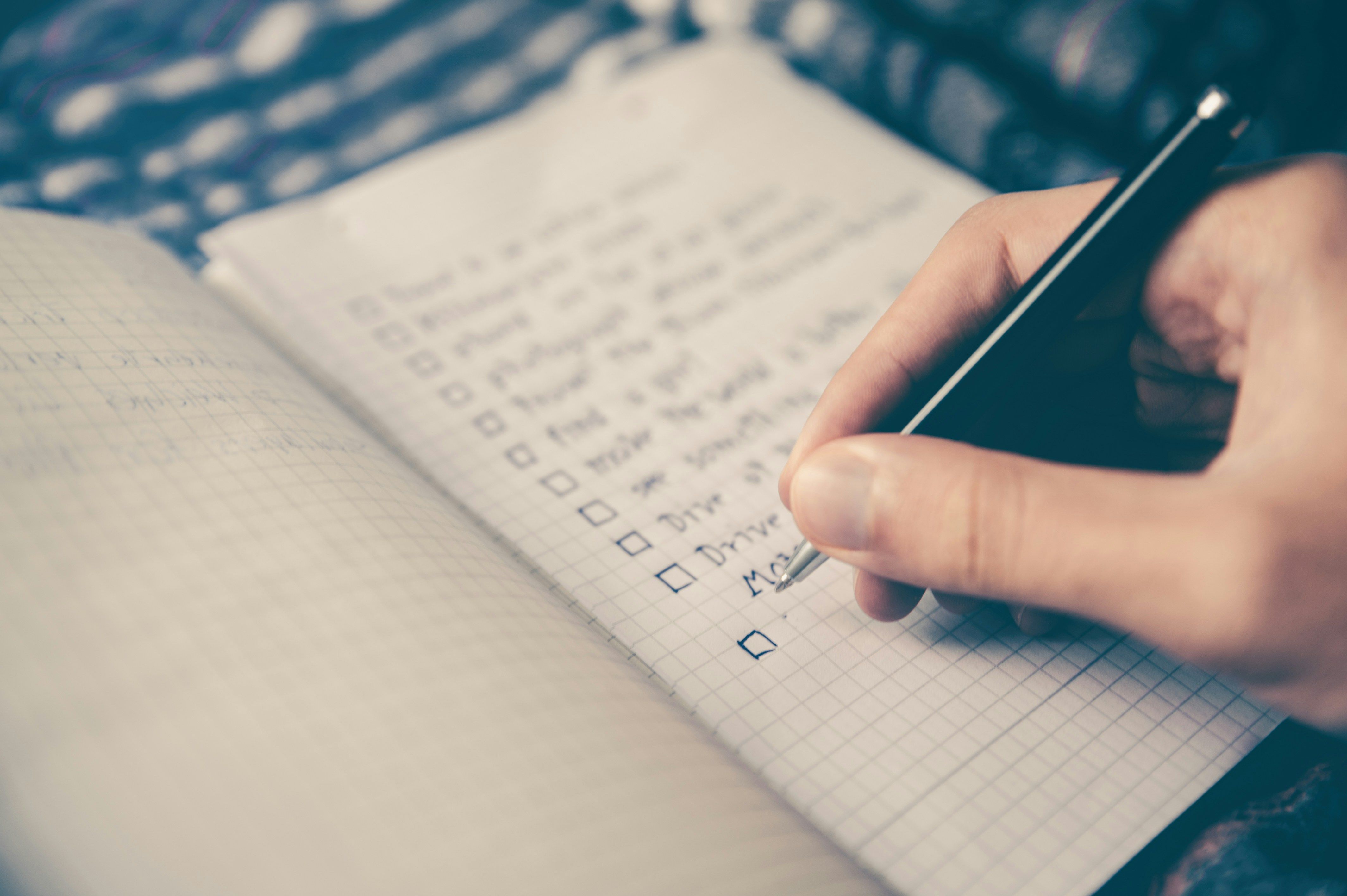A person writing a checklist on a notepad