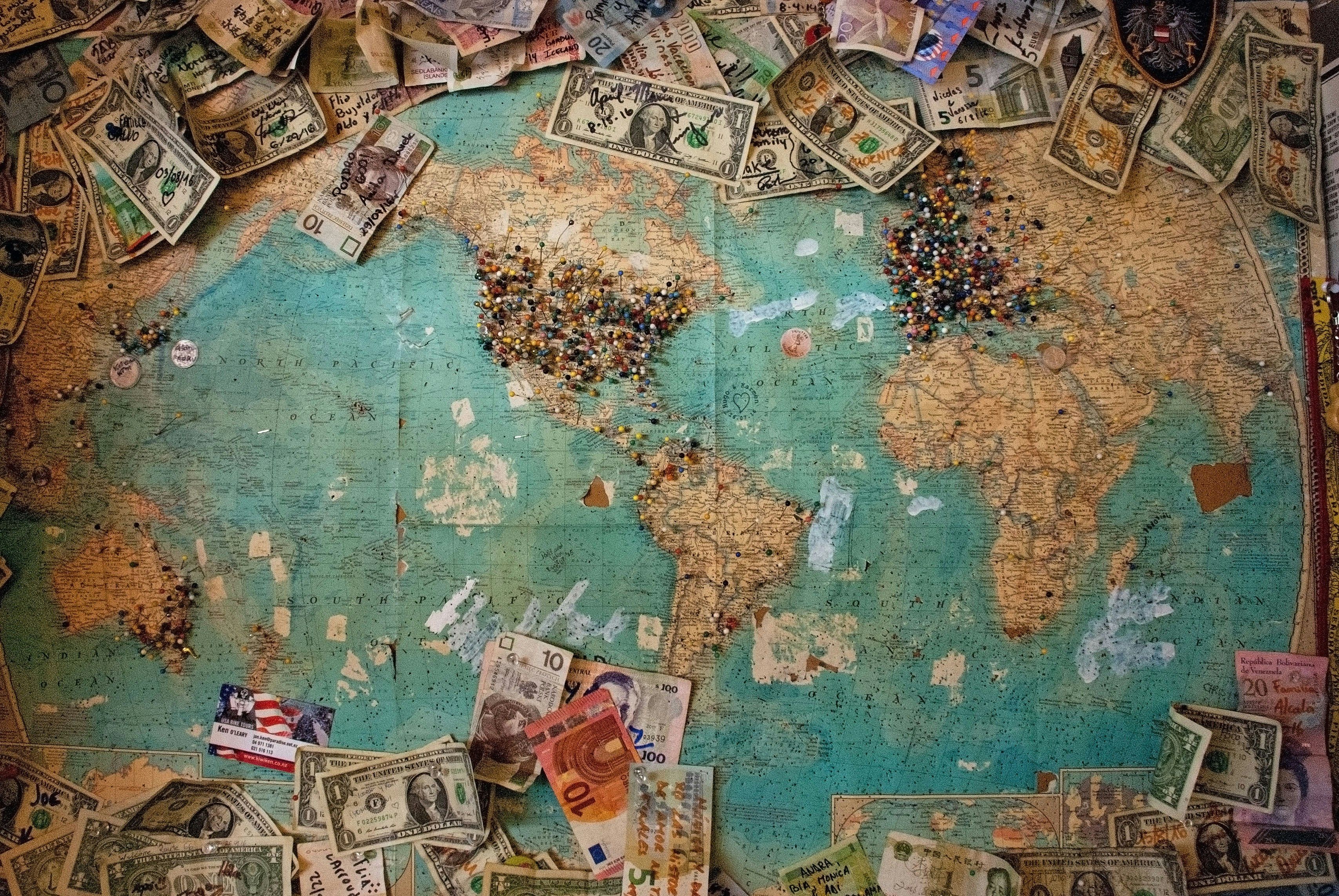 A world map with different currency notes on it