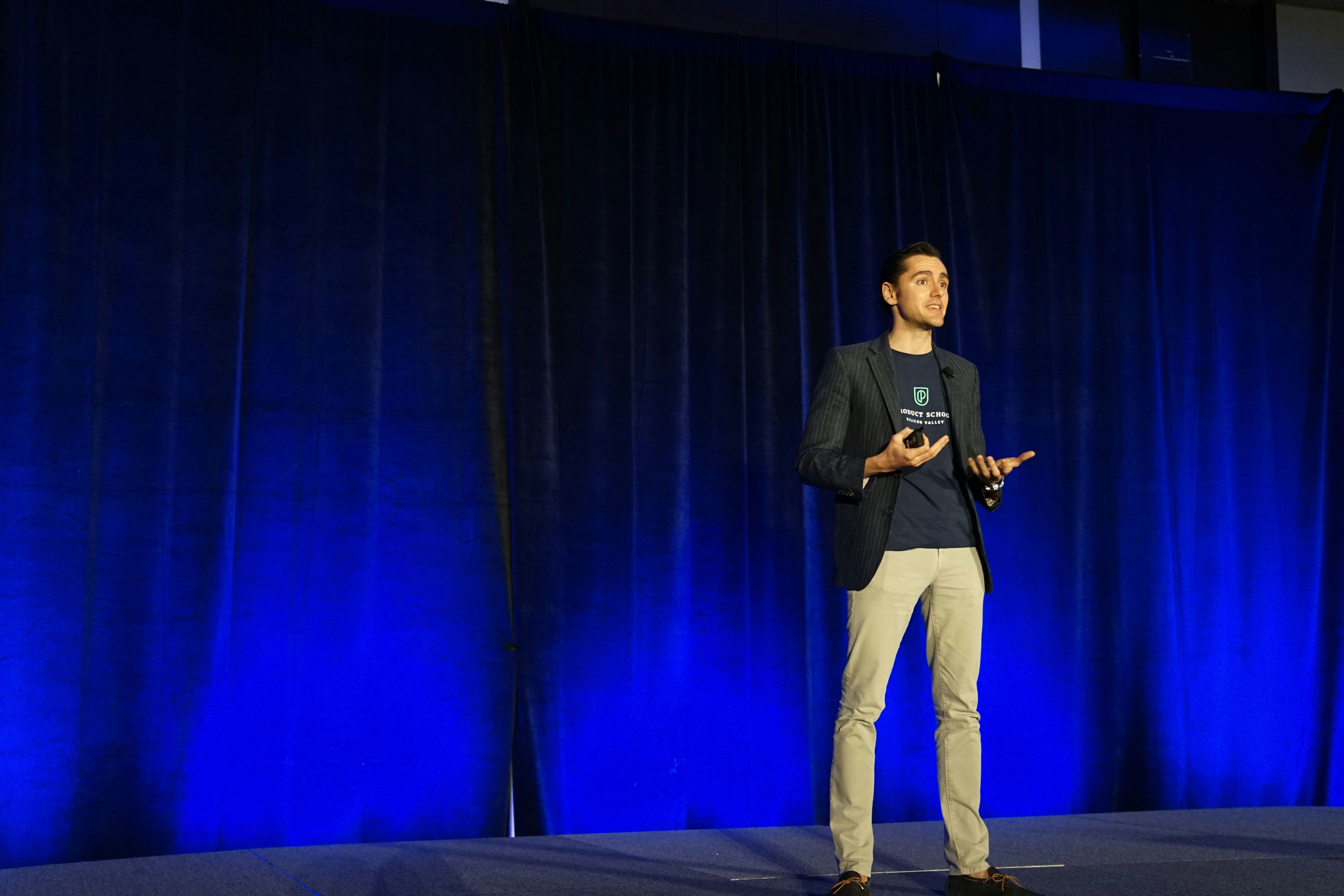 man presenting on stage to an audience