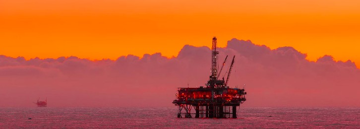 Vibrant colors of sunset accentuating an offshore oil rigs presence at sea