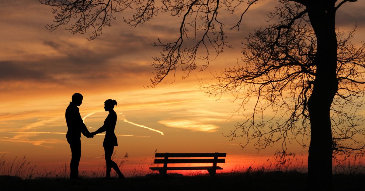 Young couple holding hands against an orange sky